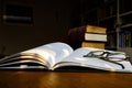 Close up of open text book with eye glasses on wooden desk in library. Old books and bookshelf background. Education Royalty Free Stock Photo