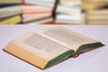 Close-up of an opened antique book on a bright table with a blurred bookshelf in a library. Education concept