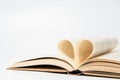 Close up of opened book with heart shaped from two pages, isolated on white background. Royalty Free Stock Photo