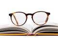 Opened book with reading glasses isolated on white background, front view Royalty Free Stock Photo
