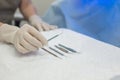 Close-up of an ophthalmologist doctor holding instruments for microscopic eye surgery in his hand over a sterile table