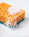 Close Up of an Orange and Green Cleaning Sponge with Soap Bubbles on White Background Royalty Free Stock Photo