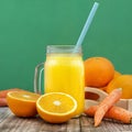 Orange juice and carrot juice, in the glass jar. Green background. Healthy, vegan food and drinks Royalty Free Stock Photo