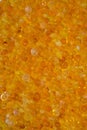 Close up of orange silica gel dessicant. Golden translucent beads with shiny light