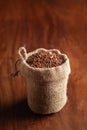 Close-up of Organic Brown flaxseeds Linum usitatissimum or linseed in a standing jute bag over wooden brown background