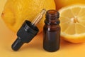 Whole lemons and half lemon with a flask of essential oil close-up on yellow background