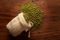 Close-up of Organic green Gram Vigna radiata or whole green moong dal spilled out from a laying jute bag over wooden Royalty Free Stock Photo