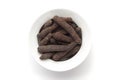 Close-up of Organic Indian long pepper Piper retrofractum on a ceramic white bowl. Pile of Indian Aromatic Spice