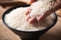 Organic Thai Jasmine rice grain in a black bowl with hand Royalty Free Stock Photo