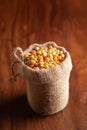 Close-up of organic yellow corn seed or maize Zea mays in a standing jute bag over wooden brown background Royalty Free Stock Photo