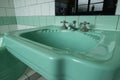 Close up of original green vintage retro 1930s deco wash basin and stainless steel taps. Royalty Free Stock Photo