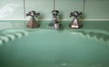 Close up of original green vintage retro 1930s deco wash basin and stainless steel taps. Royalty Free Stock Photo