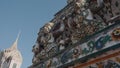 close-up of the ornate architectural details of Wat Arun, with intricate statues and colorful floral-patterned