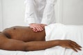 Close up of osteopath doing manipulative massage on african male abdomen on white background, copy space.