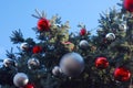 Close-up of outdoor city Christmas Tree with red globes on Blue Sky