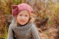 Close up outdoor portrait of adorable smiling child girl in pink knitted hat and grey sweater Royalty Free Stock Photo