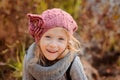 Close up outdoor portrait of adorable smiling child girl in pink knitted hat and grey sweater Royalty Free Stock Photo