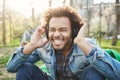 Close-up outdoor portrait of handsome african man with afro haircut holding hands on headphones while listening to music Royalty Free Stock Photo