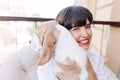 Close-up outdoor portrait of smiling girl with dark-brown hair holding beagle dog. Stunning brunette lady in white