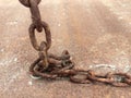 Close up outdoor view dirty ground and brown color, of an ancient rusty chain placed on the ground.