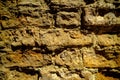 Close-up outdoor view of part of an ancient stone wall with a textured surface. An abstract image of a brown cemented