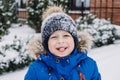 Close up outdoor winter portrait of boy face in the snow. Authentic, real, candid portrait of cute boy in winter time