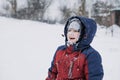 Close up outdoor winter portrait of boy face in the snow. Authentic, real, candid portrait of cute boy in winter time