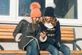 Close-up outdoor winter portrait of two teenage girls students in profile smiling and talking, girls looking at mobile phone Royalty Free Stock Photo