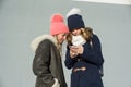 Close-up outdoor winter portrait of two teenage girls students in profile smiling and talking, girls looking at mobile phone Royalty Free Stock Photo