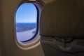 Close up of oval airplane window and back of economy seat with blue sky. transportation and Travel Concept Royalty Free Stock Photo
