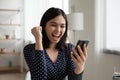 Close up overjoyed Asian woman reading good news, celebrating success