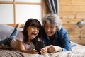 Close up overjoyed little girl with grandmother using phone together