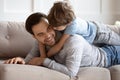 Close up happy father and son hugging, lying on couch Royalty Free Stock Photo