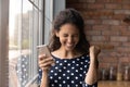 Close up overjoyed woman holding phone, celebrating success, good news