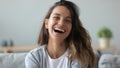 Close up overjoyed woman laughing, sitting on couch at home