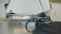 Close-up, the overstitching machine passes the edges of the black fabric in slow motion. Serger process in the sewing