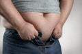 Close up of overweight man trying to wear small jeans