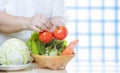 Close up of overweight woman hand preparing various organic vegetables into bamboo basket for cooking on kitchen table Royalty Free Stock Photo