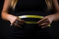 Close up of overweight woman measuring her waist with a yellow measuring tape, Woman measuring her waist with a tape measure on a Royalty Free Stock Photo
