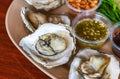 Close-up oysters in serving plate, medium grilled oysters with spicy seafood sauce, chilli plate, deep-fried shallot and Acacia