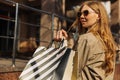 Close-up packages. women hold shopping bags on the street, woman in beige raincoat and sun goggles Royalty Free Stock Photo