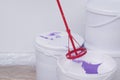 Close-up of paint buckets and a stirrer, against a white wall