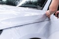 Paint protection film installation on white car fender during professional PPF car detailing Royalty Free Stock Photo