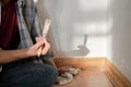 Close up of painter arm in splattered paint shirt holds a paint brush, painting wall in white color Royalty Free Stock Photo