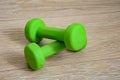 Close-up of a pair of bright green little female dumbbells on the wooden floor