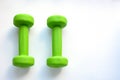 Close-up of a pair of bright green small female dumbbells on a white plastic table