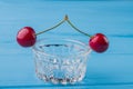 Close-up pair of cherries on a transparent glass cup for sauce.
