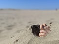 Close up of a pair of feet and toes sticking out of beach sand