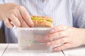 Close up on pair of female hands removing a healthy wholesome wholemeal bread ham sandwich from her lunch box during lunch break Royalty Free Stock Photo