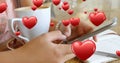 Close up of a pair of female hands texting beside a cup of coffee and a pen and notebook